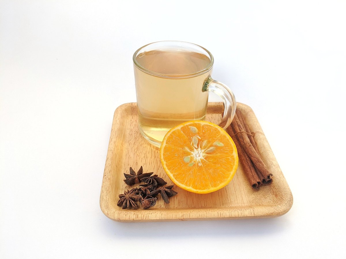 A warm cup of Somali spiced tea with coffee beans, cinnamon and cardamom on a wooden table
